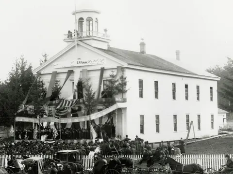 An old photograph of the wooden Territorial Capitol in Olympia, hung with flags and bunting.